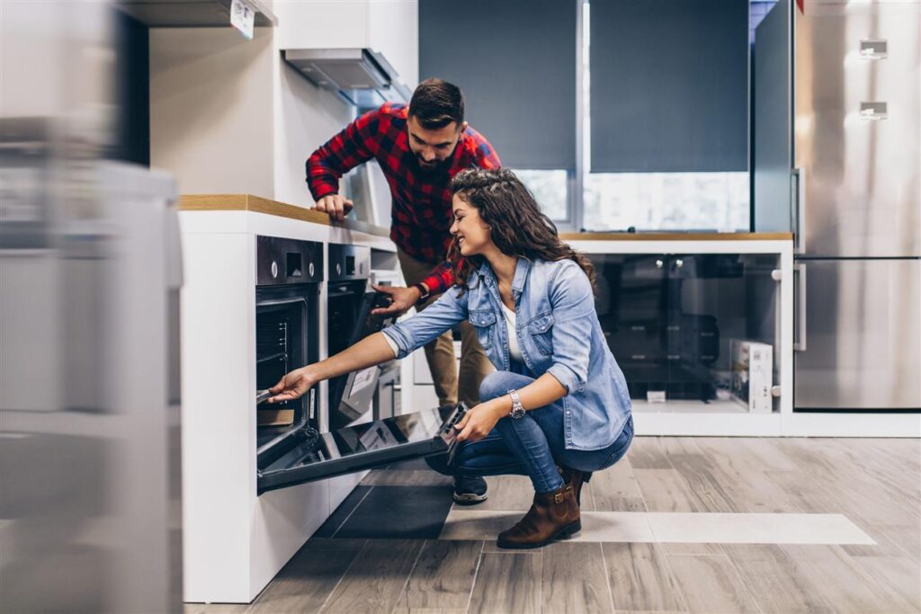 Happy young couple buying household appliances in store