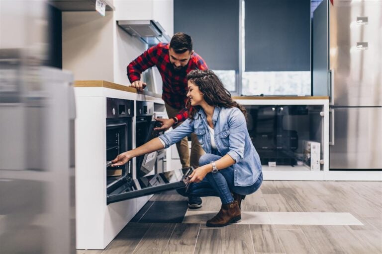 Happy young couple buying household appliances in store