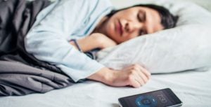 Woman Sleeping On Bed With Alarm On Mobile Phone